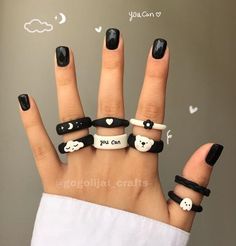 a woman's hand with black and white nail polish holding five rings that say you can