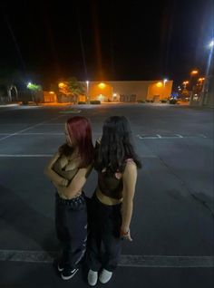 two women standing in an empty parking lot at night