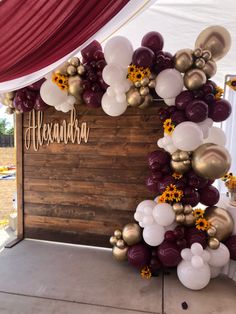 the balloon arch is decorated with sunflowers and white, red, and gold balloons