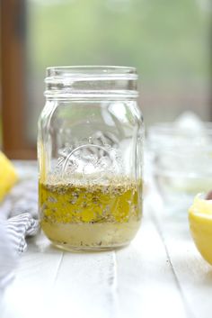 a jar filled with liquid sitting on top of a wooden table next to lemons