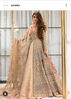 a beautiful woman in a long dress standing on a stage wearing a gold and beige outfit