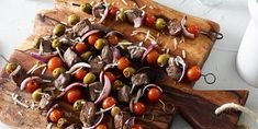 a wooden cutting board topped with meat and veggies on top of a table