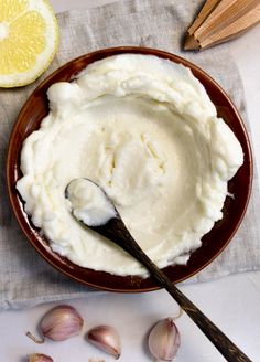 garlic dipping sauce in a bowl with lemons on the side