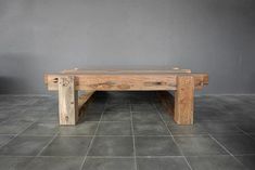 a wooden bench sitting on top of a tile floor next to a gray wall in a room