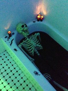 a skeleton sitting in a bathtub with candles