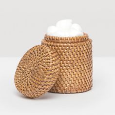 a wicker basket with cotton in it on a white surface, next to the lid