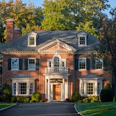 a large red brick house with white trim and black shutters on the front door