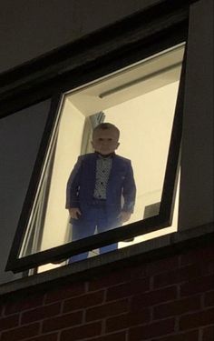 a man in a blue suit looking out the window at something on the wall behind him