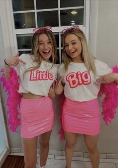 two girls in matching shirts and pink feathered skirts posing for the camera with their arms around each other