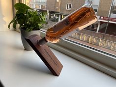 a bottle of alcohol sitting on top of a window sill next to a potted plant