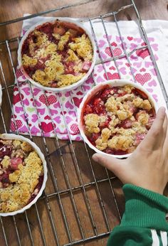 three bowls of food sitting on top of a metal rack next to a person's hand