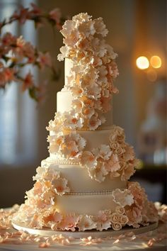 a three tiered wedding cake with flowers on the top and bottom, sitting on a table