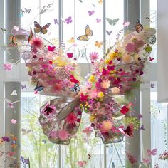 a large butterfly made out of flowers sitting on top of a table next to a window