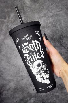 a hand holding a black coffee cup with a skull on it and the words goth juice written