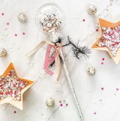 three star shaped ornaments on a table with silver and pink stars around them, one is filled with confetti