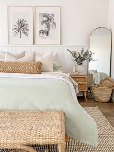 a bedroom with two pictures on the wall above the bed and wicker foot stool