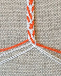 an orange and white piece of yarn with two ends on top of the other end