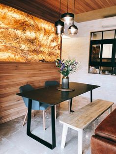 a wooden table and bench in front of a large piece of art on the wall