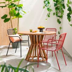 an outdoor table with four chairs around it and a potted plant in the background