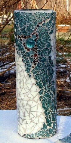 a vase sitting on top of a table covered in white and green shards with a blue heart