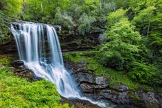 a large waterfall surrounded by lush green trees