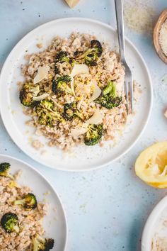 rice and broccoli are served on two white plates with lemon wedges next to them