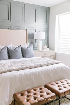 a bedroom with a bed, two stools and a lamp on the side table