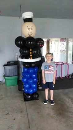 a young boy standing next to an inflatable balloon sculpture that looks like a man