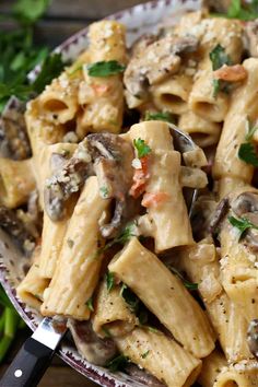 a bowl full of pasta with mushrooms and parsley