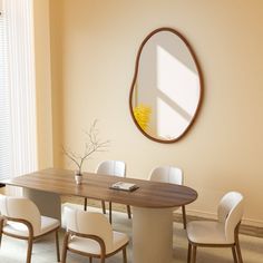 a dining room table with white chairs and a round mirror on the wall