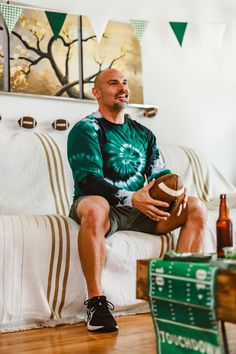 a man sitting on top of a couch holding a football