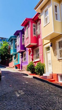 a car parked on the side of a cobblestone road in front of multi - colored houses