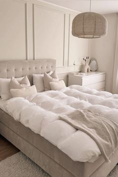 a large bed sitting in a bedroom next to a window covered in white sheets and pillows