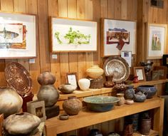 there are many vases and bowls on the shelves in this room with wood paneling