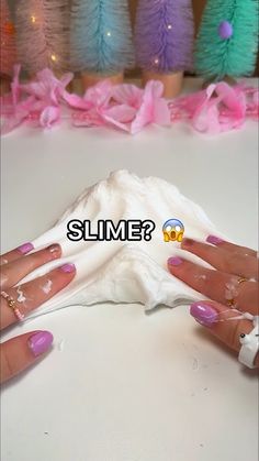 a woman's hands with pink and white nail polish are shown in front of some fake trees