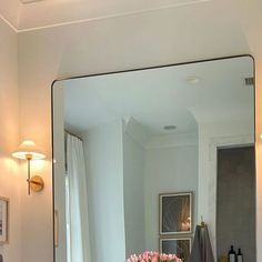 a bathroom with a sink, mirror and flowers in the vase on the counter top