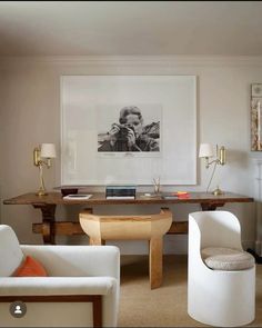 a living room with two chairs and a table in front of a painting on the wall