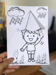 a person holding up a paper cut out of a child's head with rain coming from it