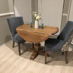 a dining room table with two chairs and a vase on top of it in front of a window