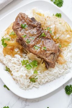 a white plate topped with rice and meat next to parsley on top of it