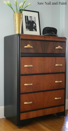 an old dresser with some flowers on top and a gold vase in the corner next to it