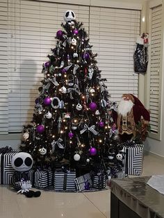 a decorated christmas tree in the corner of a living room with black and purple decorations