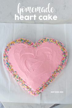 a heart shaped cake with pink frosting and sprinkles in the shape of a heart