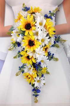 a bride holding a bouquet of sunflowers and daisies