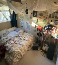 an unmade bed in a bedroom with lots of clutter on the walls and floor