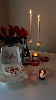 a table topped with candles and plates filled with cake next to bottles of wine on top of a table