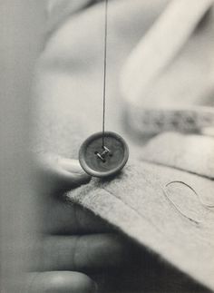 a person holding a sewing needle with a button on it