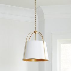 a white lamp hanging from a ceiling in a living room with a window behind it