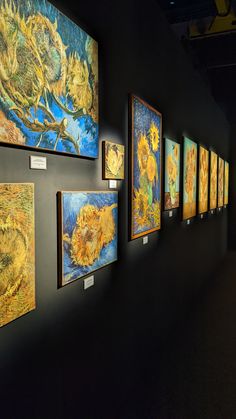 art work displayed on wall in dark room with yellow and blue paintings hanging from the ceiling