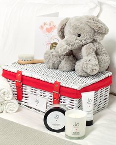 a stuffed elephant sitting on top of a wicker basket next to a candle and other items